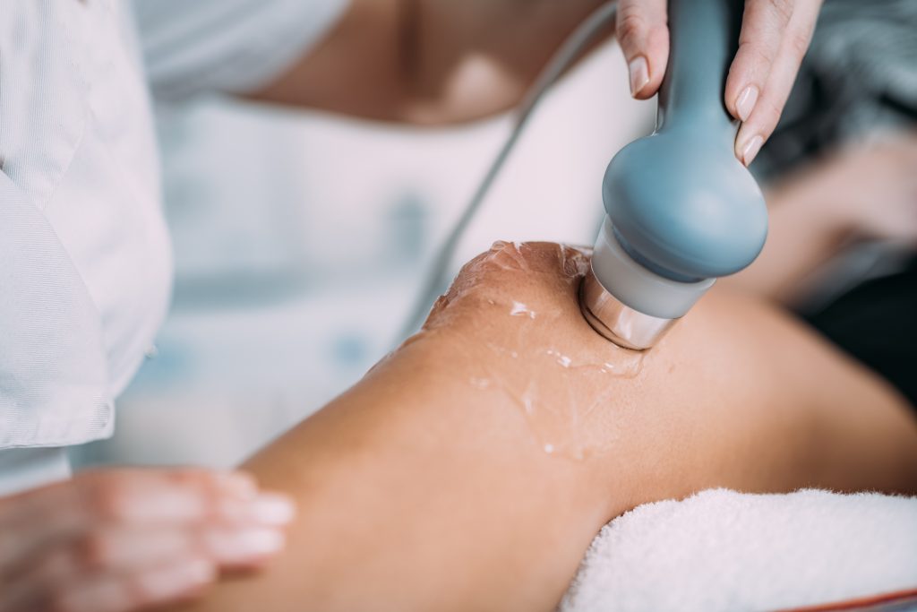 Therapeutic ultrasound used in physical therapy. Therapist is using ultrasound on patient's knee.