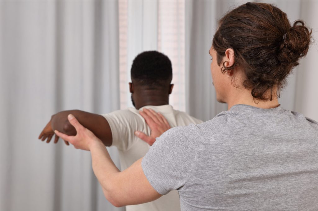 Image shows physiotherapist helping a man with his range of motion.