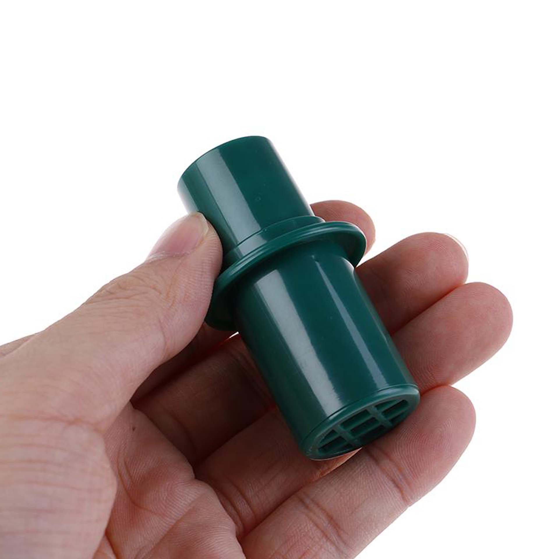Image of a green CPR practice mask valve being held by a hand