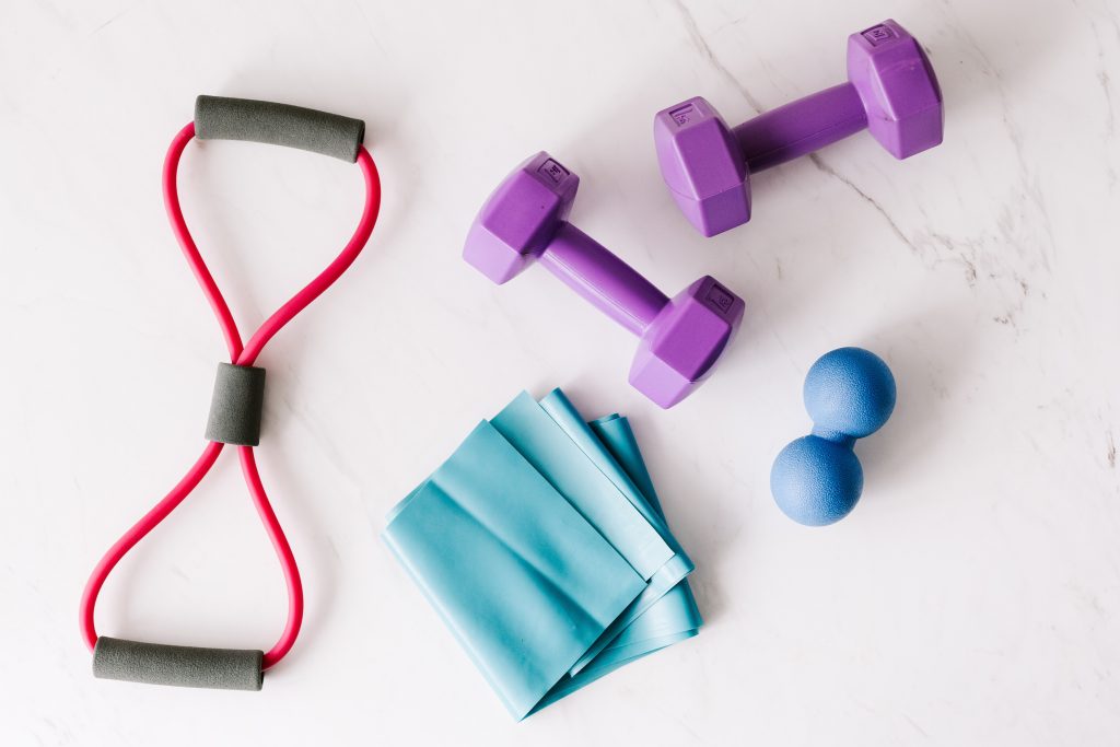 image shows gym equipment like thera tubes, dumbbells, thera bands, and thera balls
