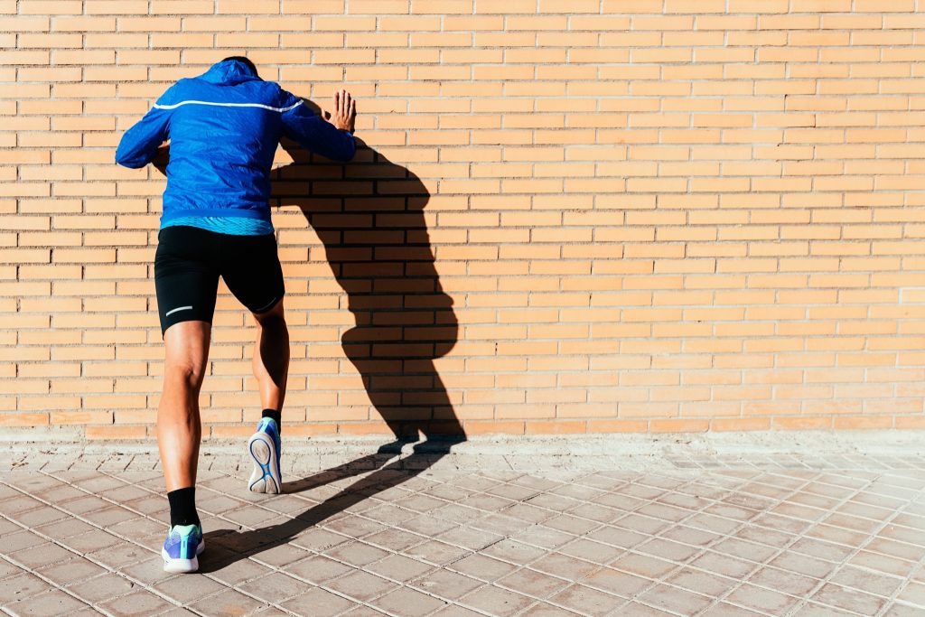 Man stretching his calves against the wall.