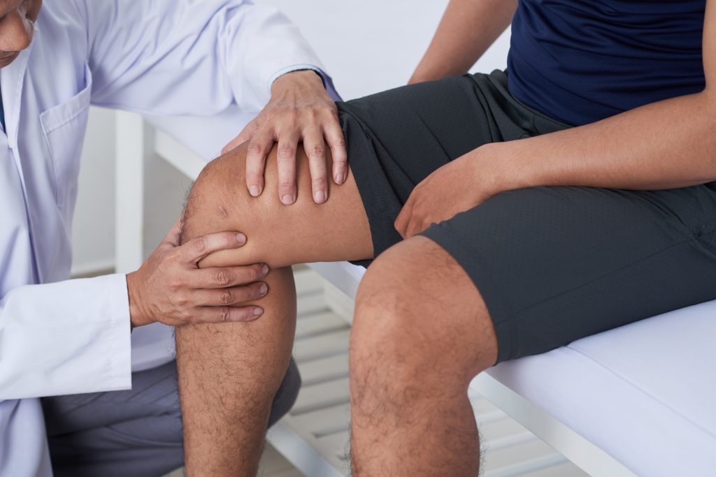 Doctor examining patient's knee to check for injuries to the acl or pcl