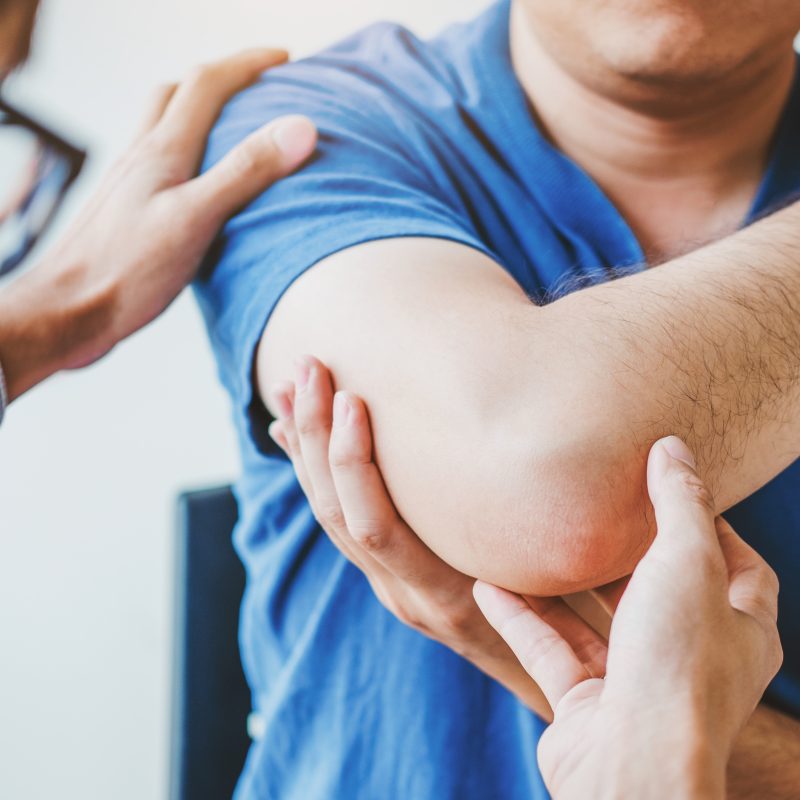 Doctor examining patient's elbow to determine possible tennis elbow or golfer's elbow injury.