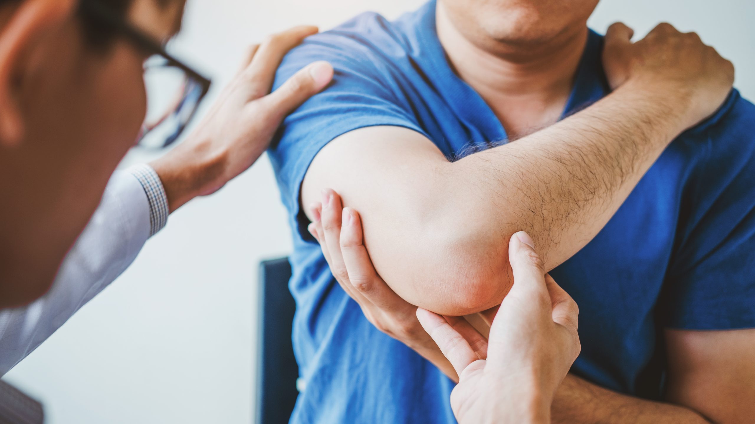 Doctor examining patient's elbow to determine possible tennis elbow or golfer's elbow injury.