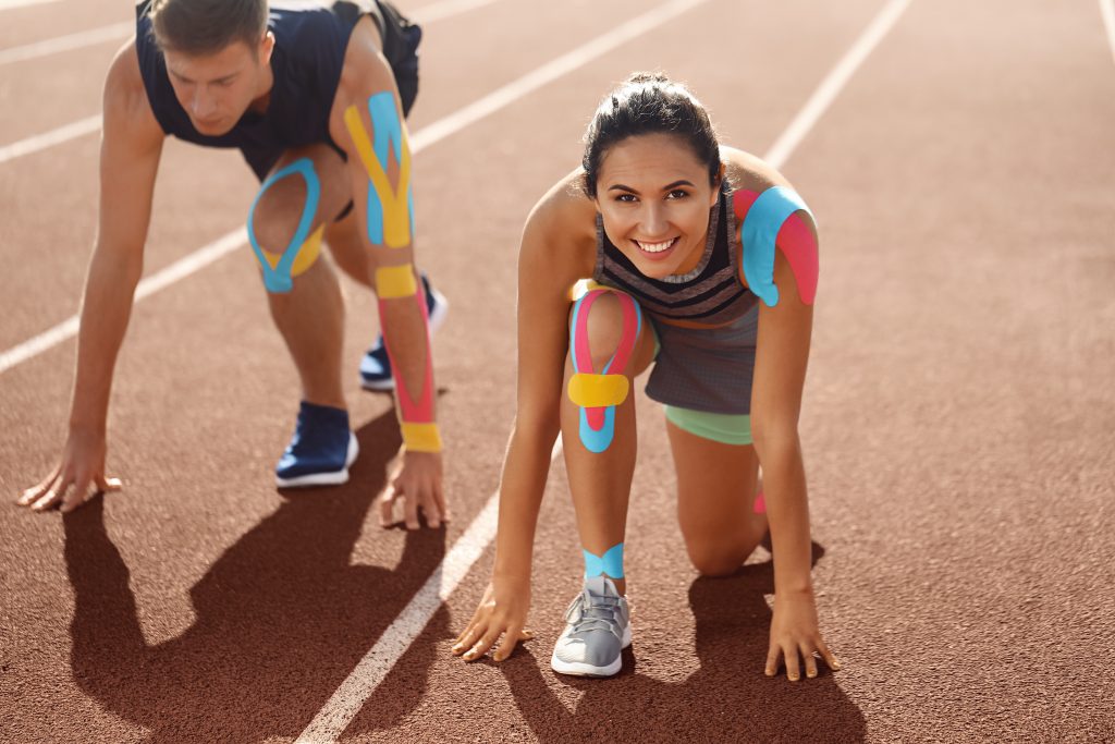 man and woman wearing kinesiology tape while preparing to run