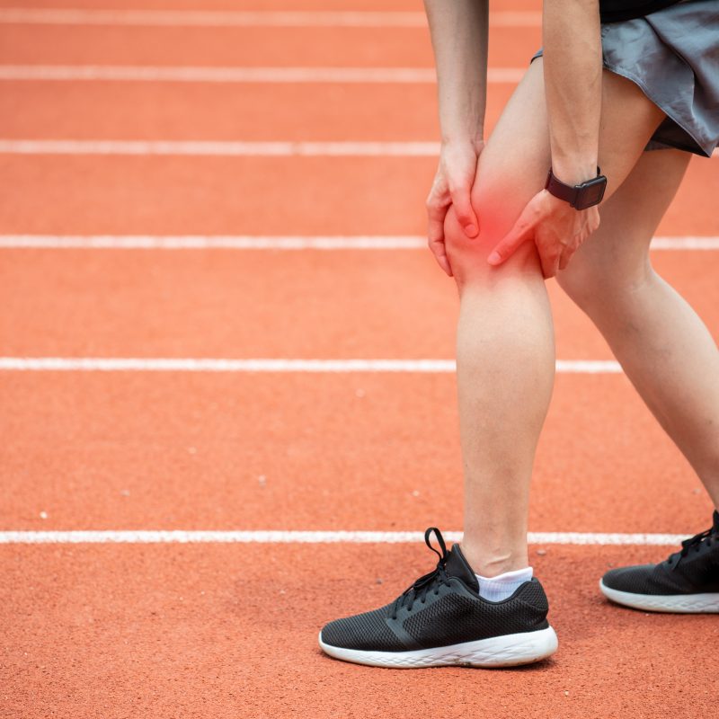 Runner holding her leg possibly suffering from iliotibial band syndrome.