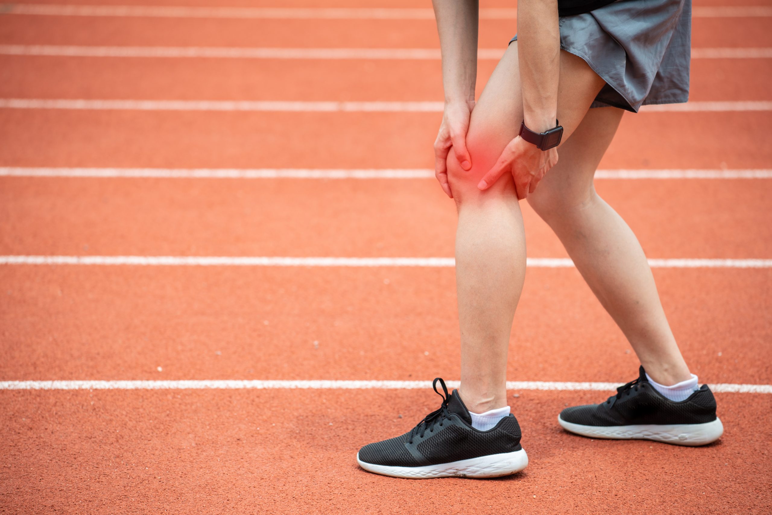 Runner holding her leg possibly suffering from iliotibial band syndrome.