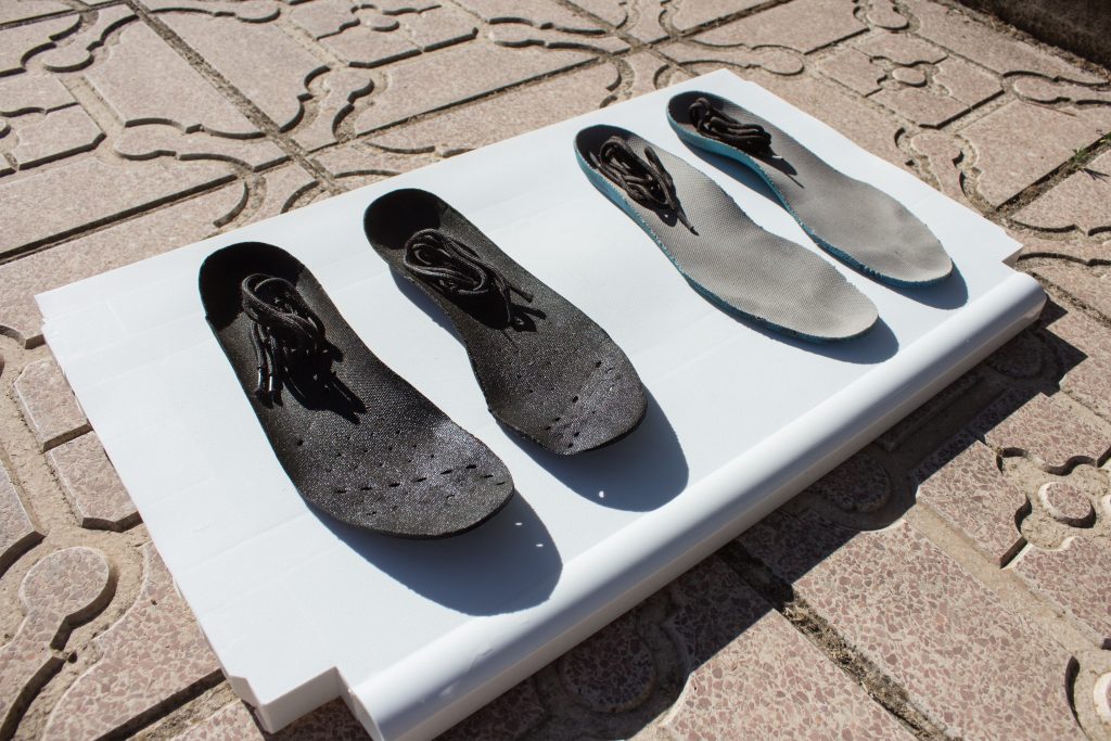 Shoe insoles with laces drying out in the sun.