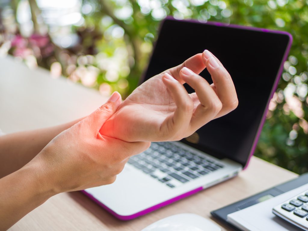 image shows woman holding her wrist possibly due to pain related to carpal tunnel syndrome