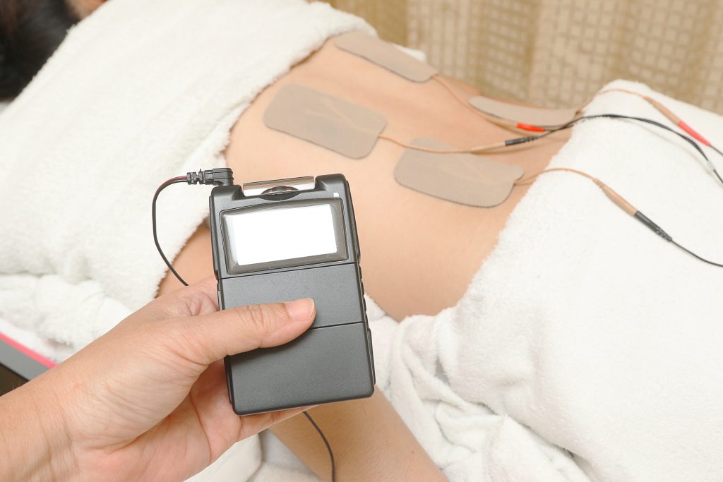 TENS therapy with tens pads placed on patient's back.