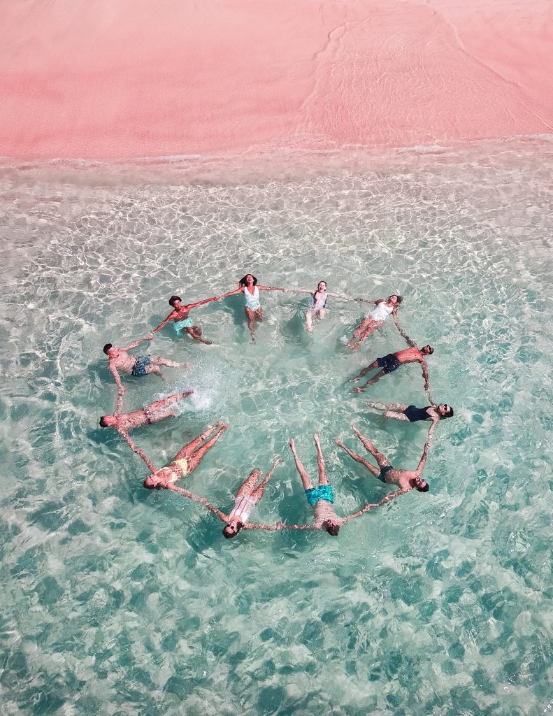 Image shows a group of people having fun swimming at the sea.