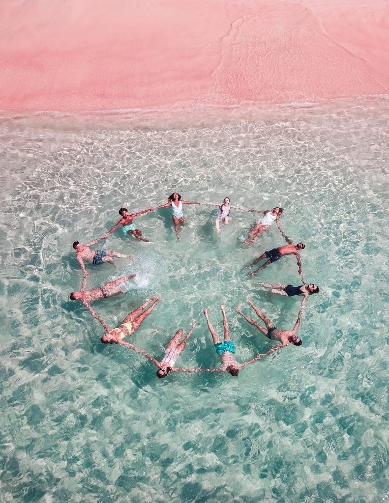 Image shows a group  of people having fun swimming at the sea.