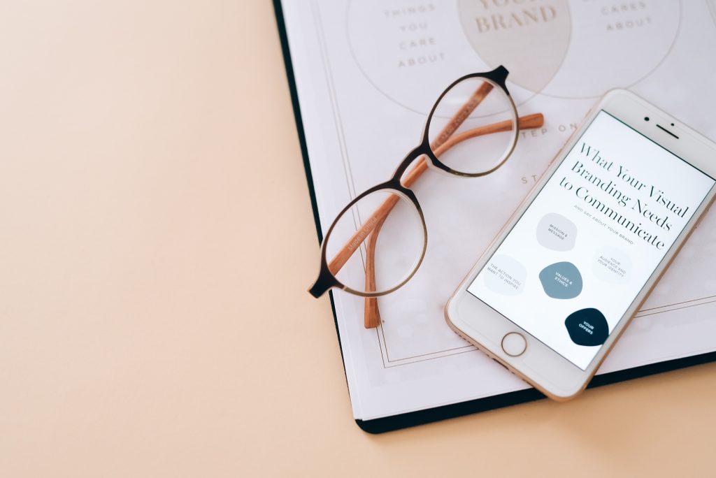 some papers, glasses, and an open phone on a table