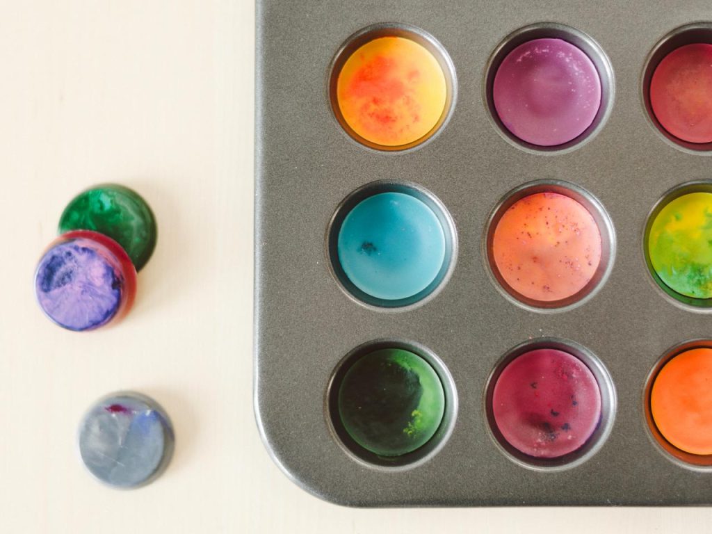 A tray of homemade crayons and modeling clay on a table