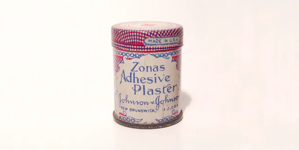 A vintage canister of Zonas Adhesive Plaster with a pinkish background
