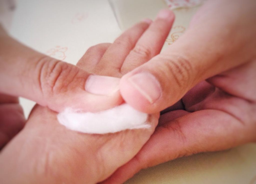 A person putting a bit of a paraffin wax on another person's hand for their minor cut