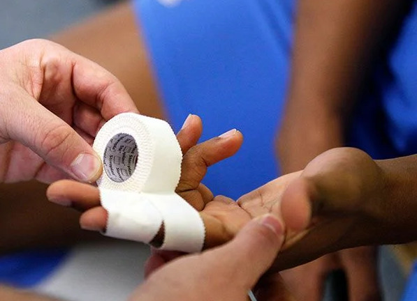 Two fingers of a hand getting the X pattern finger taping technique for cricket by another pair of hands