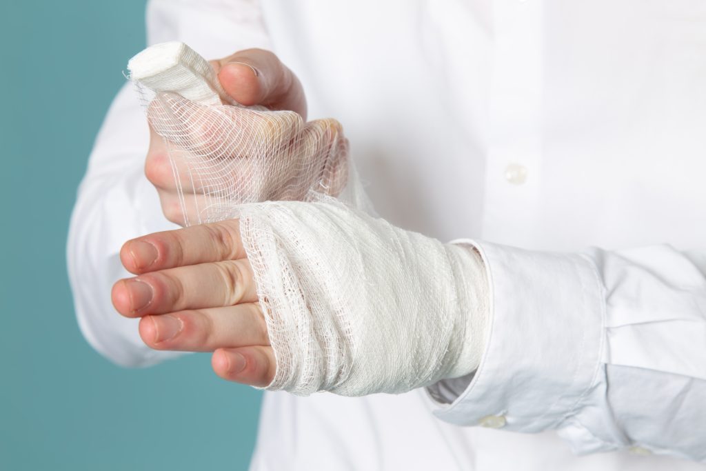 a person is removing the bandages from their hand while standing up