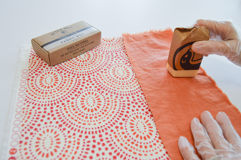 Paraffin wax being rubbed on an orange print on a table