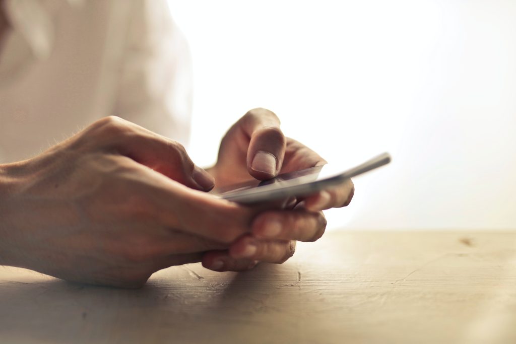 a pair of hands holding a phone while on a desk