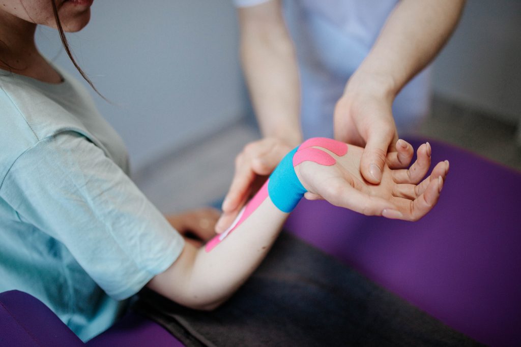 a physiotherapist layering different colored sports medicine tapes on their patient's arm