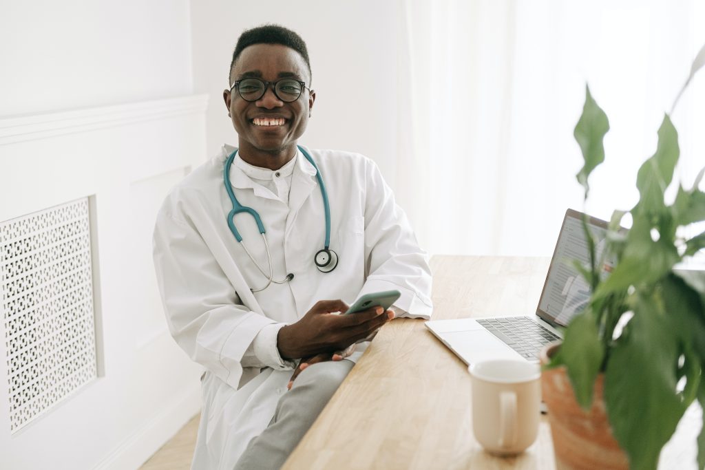 a worry-free physiotherapist while sitting down at a desk with a phone in his hands