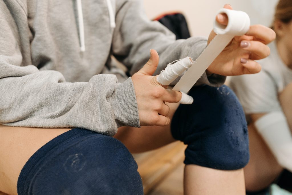 a player putting on tape around their fingers while sitting on a benchch