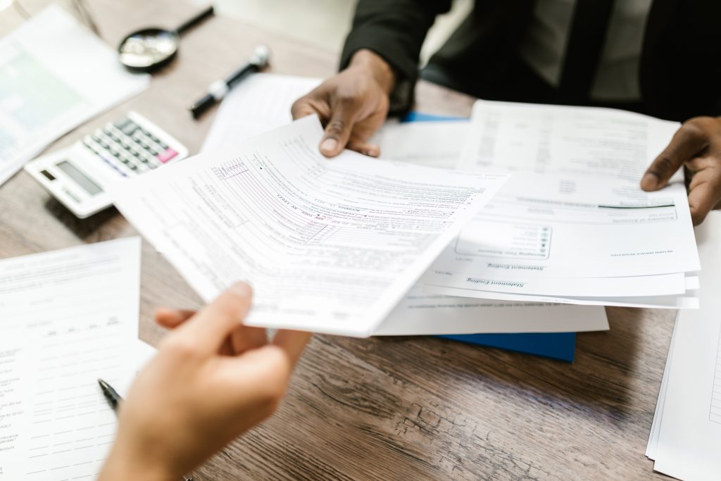 Documents being handed to another person at the other side of a desk