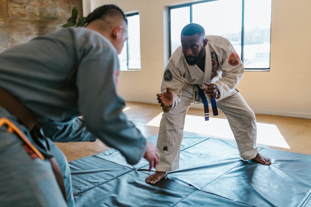 two men about to tackle one another in Brazilian jiu-jitsu while on a bluish mat