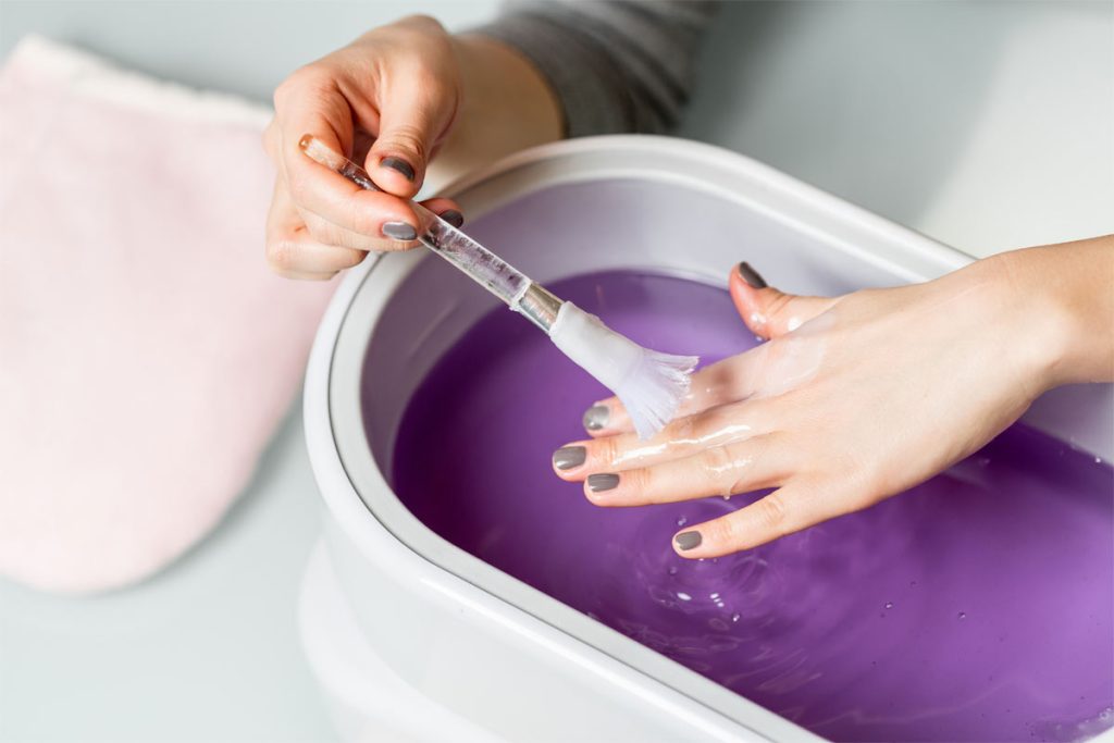 A person brushing some melted paraffin wax over their own hand