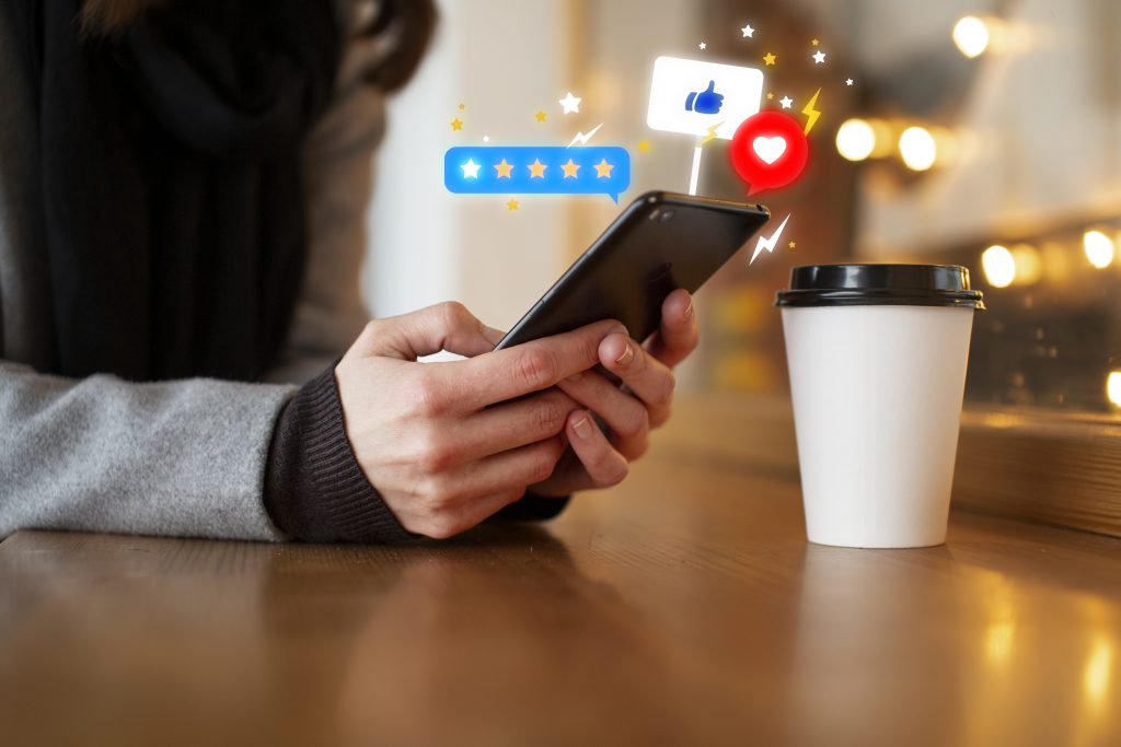 A person is showing the online ratings an reviews on their phone while leaning over a wooden table