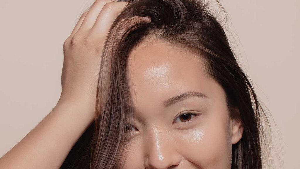 A lady is putting her hand in their hand in front of a tan background