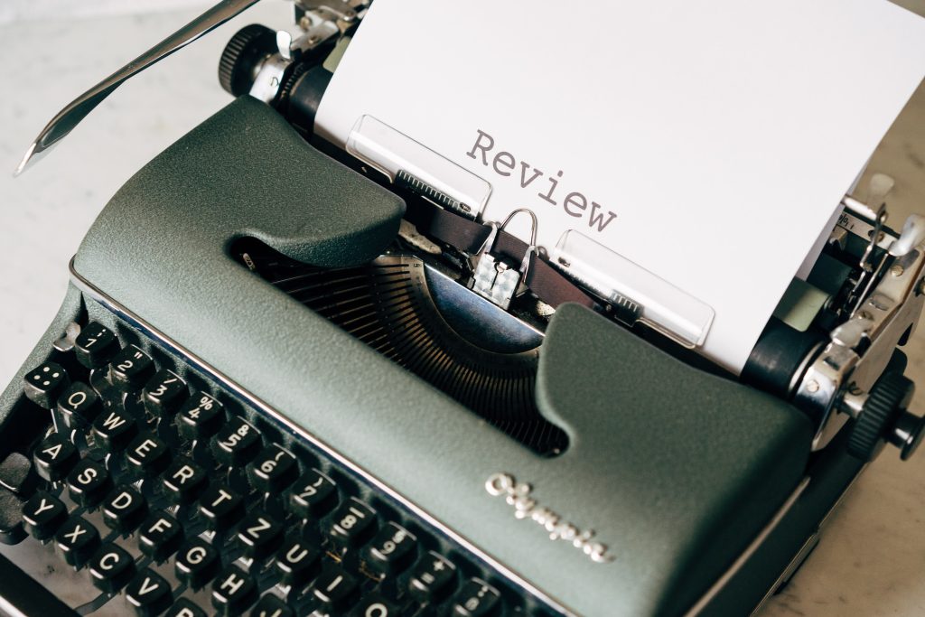 A typewriter in on a table, typing out the word review on a piece of paper
