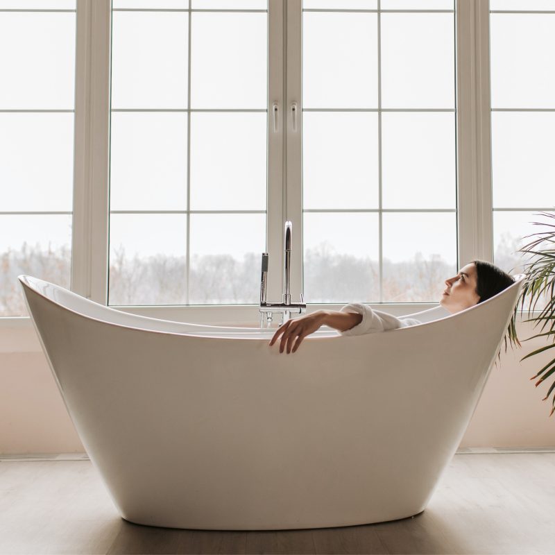 A woman is enjoying her Epsom salt bath in her spacious bathroom with very wide windows