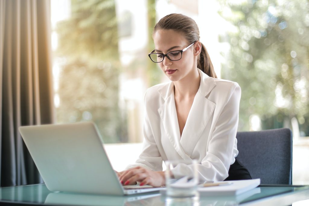 A physiotherapy clinic employee is looking through and replying to all online patient reviews while wearing glasses and a white top