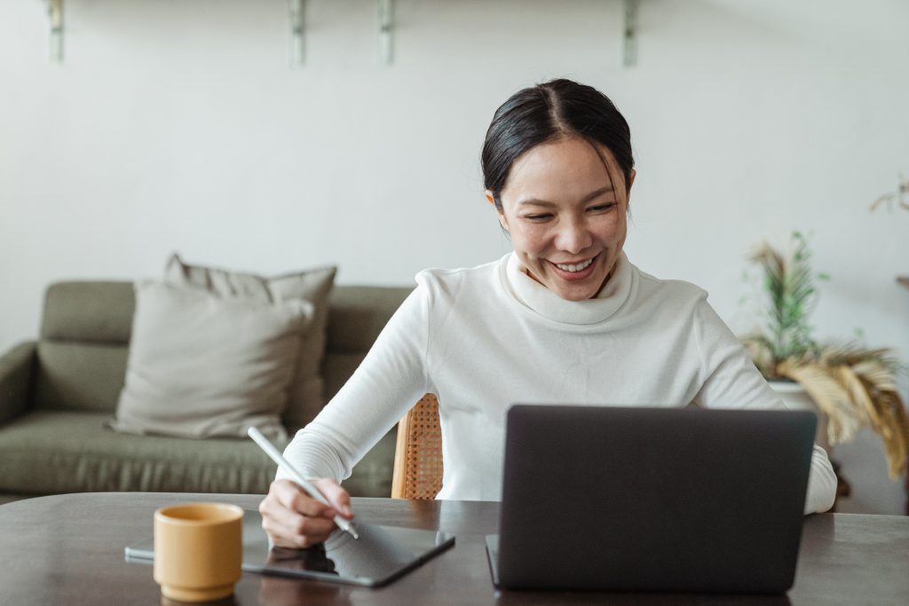 A physiotherapy clinic employee is talking privately to a patient online while wearing a white turtleneck and a smile on her face