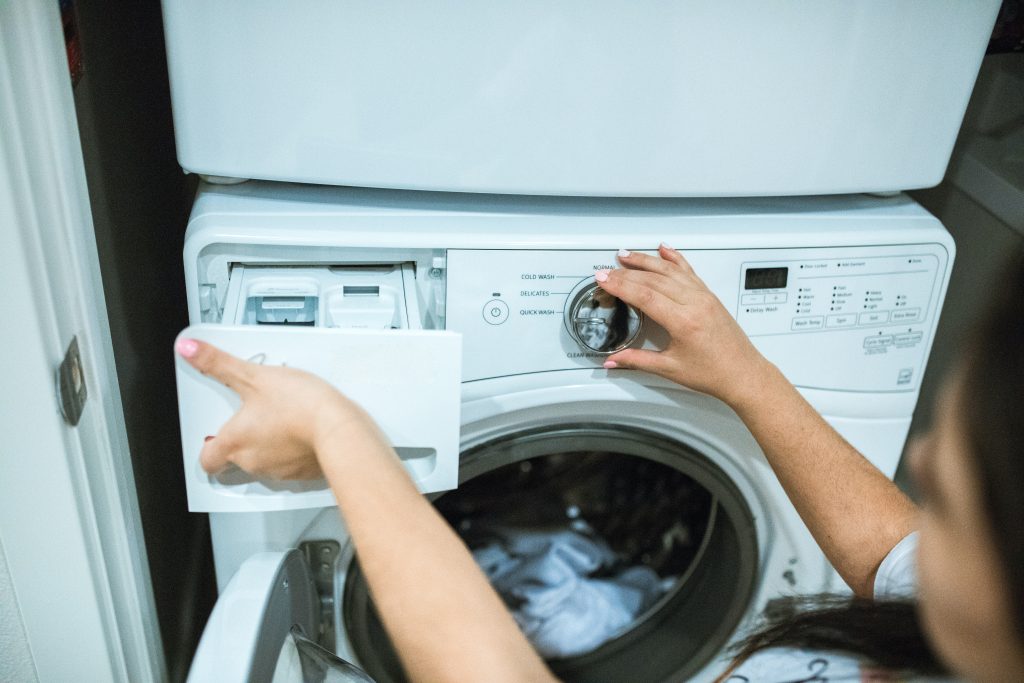 A person is putting in some Epsom salt their washing machine to wash it in a cycle