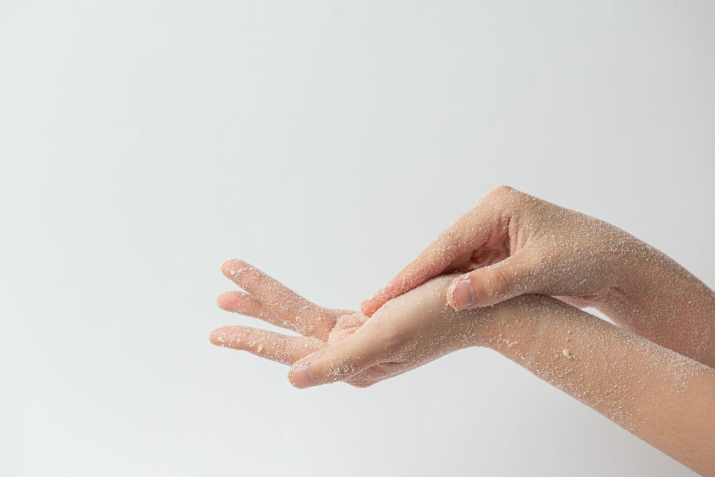 A pair of hands are rubbing on Epsom salt scrub on the palm of one hand using the other