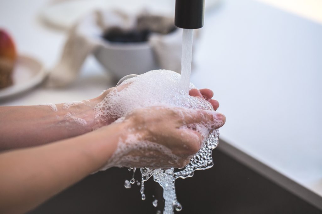 A person has their hands under a faucet of running water after washing with an Epsom salt handwash