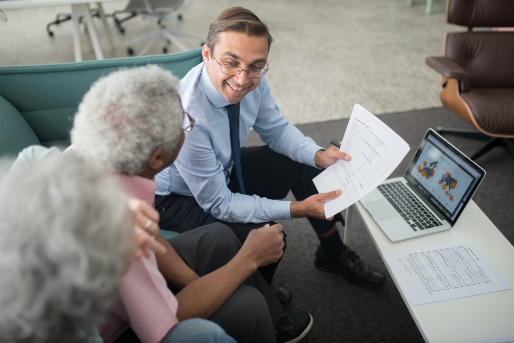 A physiotherapist is showing two potential clients the paperwork for their service which includes a satisfaction guarantee