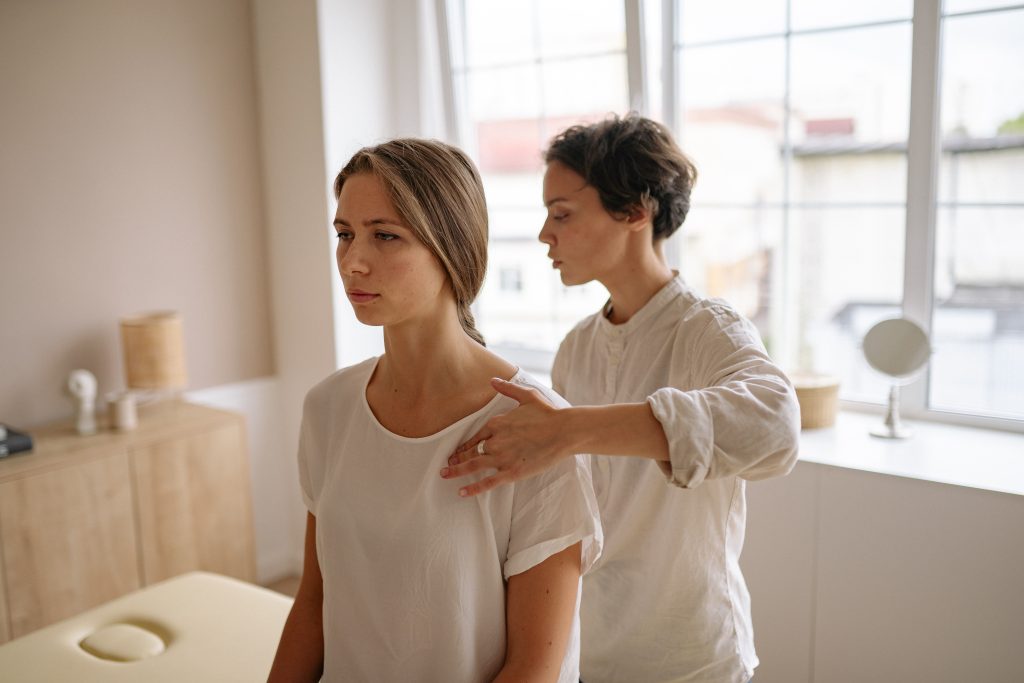 A physiotherapist is adjusting a client's back while the client is sitting down