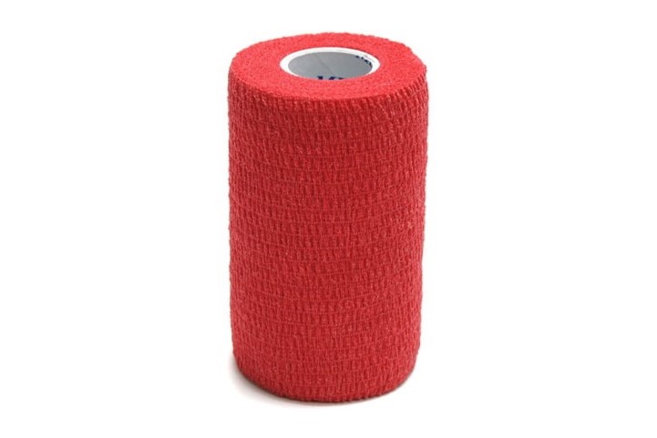 A red roll of cohesive bandage is in front of a white background and on a white table