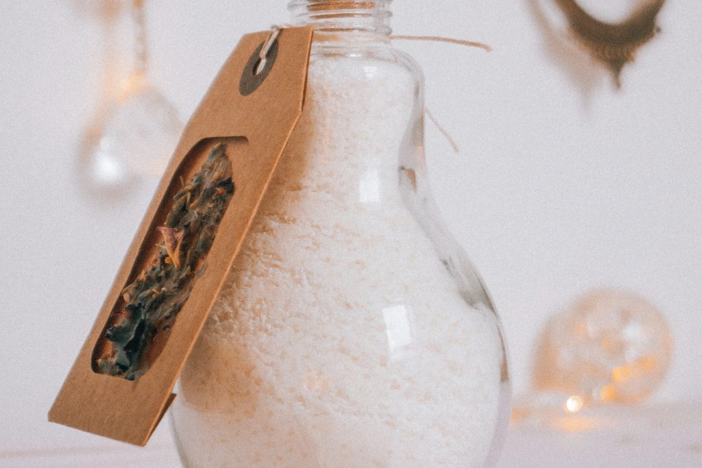 A bottle of bath salts with a brown paper tag tied together with twine