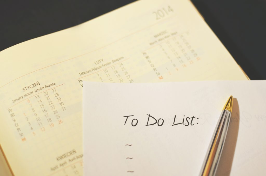 A calendar is open on a desk while there's a to-do list and a pen is on top of it