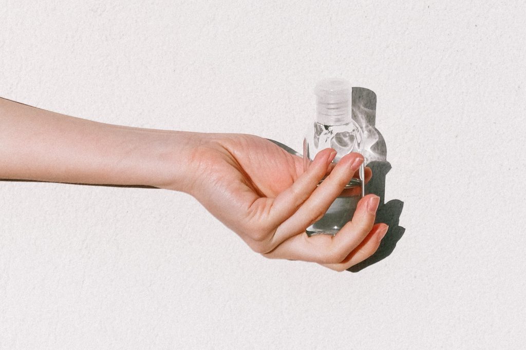 A well-manicured hand is holding a clear bottle of an antiseptic in very good lighting