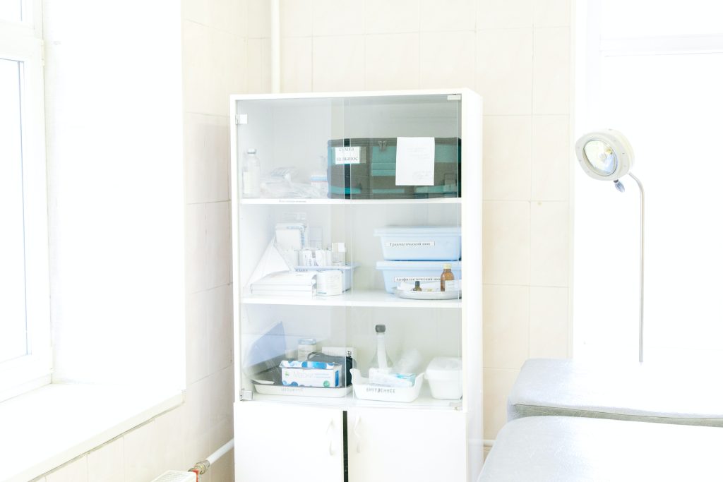 A supply cabinet for a physiotherapy clinic is in a bright white room, full of the supplies the medical professionals need to treat their patients