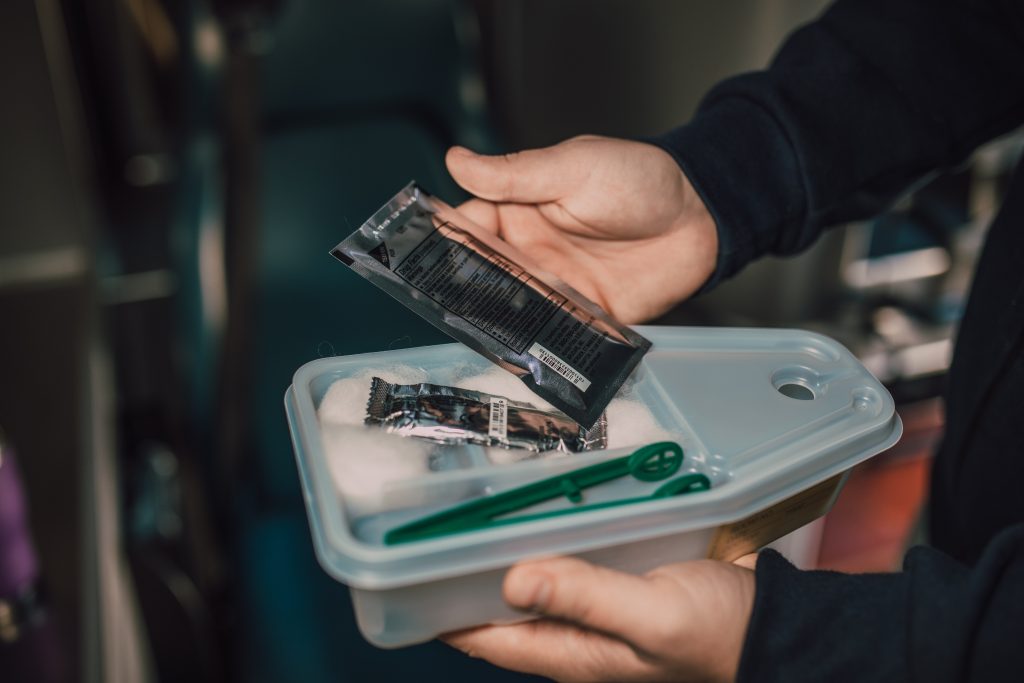 A supplier is showing the supplies they have on hand in one hand while holding the container of the supplies in the other