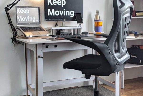 A home office setup. On the monitors is the statement: "Keep Moving.".