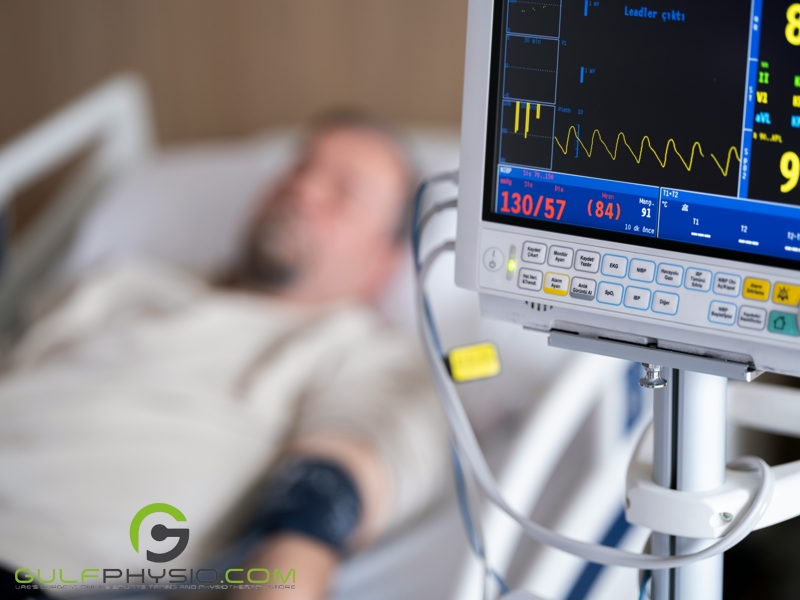 A man recovering in a hospital bed beside a heart monitor screen.