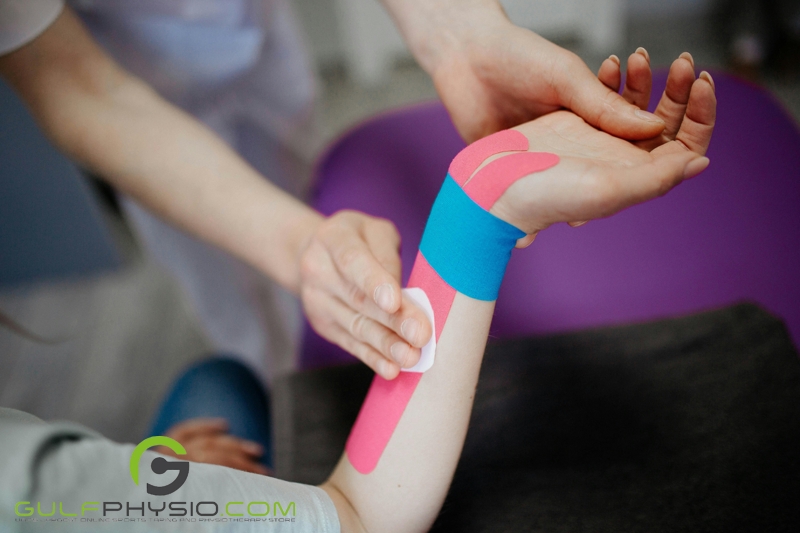 A medical professional applying a type of athletic tape to a patient's wrist and arm.